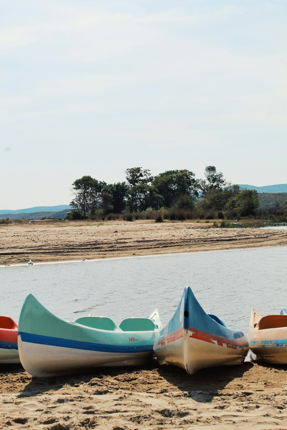 green and blue kayaks on shore during daytime