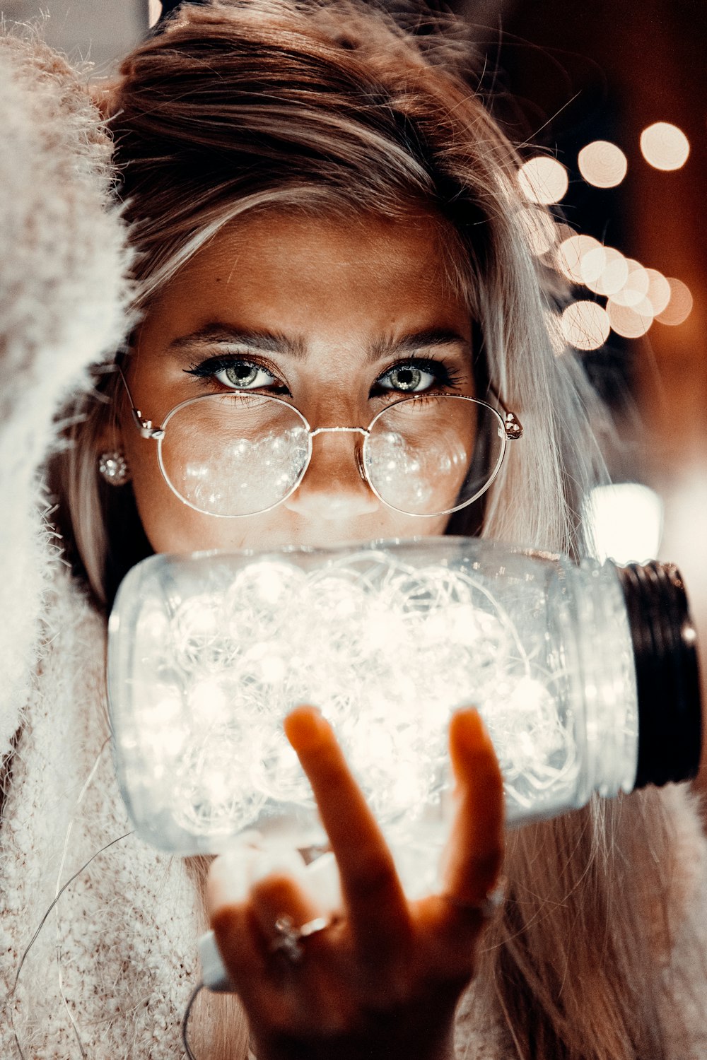 woman in white fur jacket holding clear glass jar
