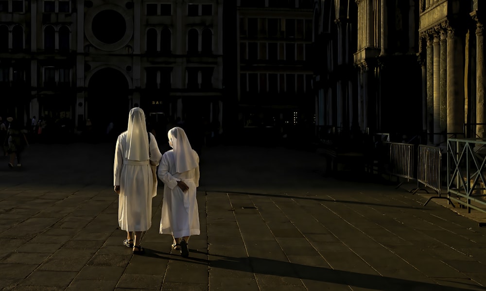 woman in white robe standing on brown brick floor during night time