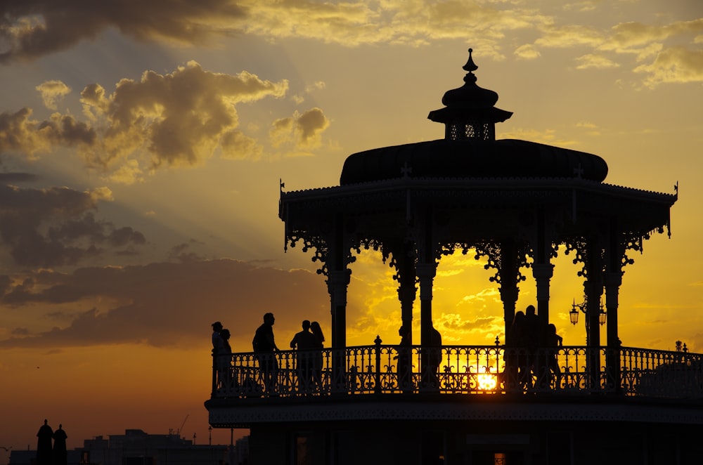 silhouette of people standing on building during sunset