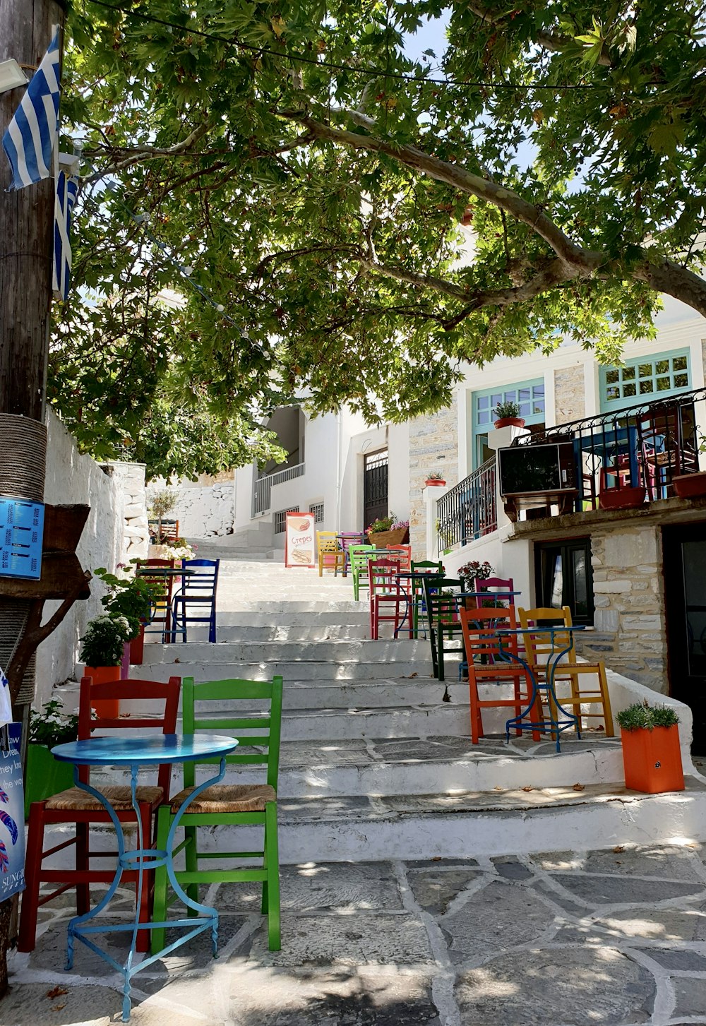 green and red wooden chairs and tables near green trees and white concrete building during daytime