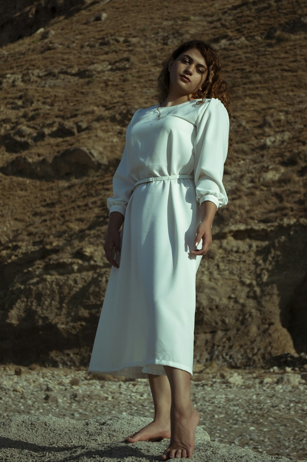 woman in white dress standing on brown sand during daytime