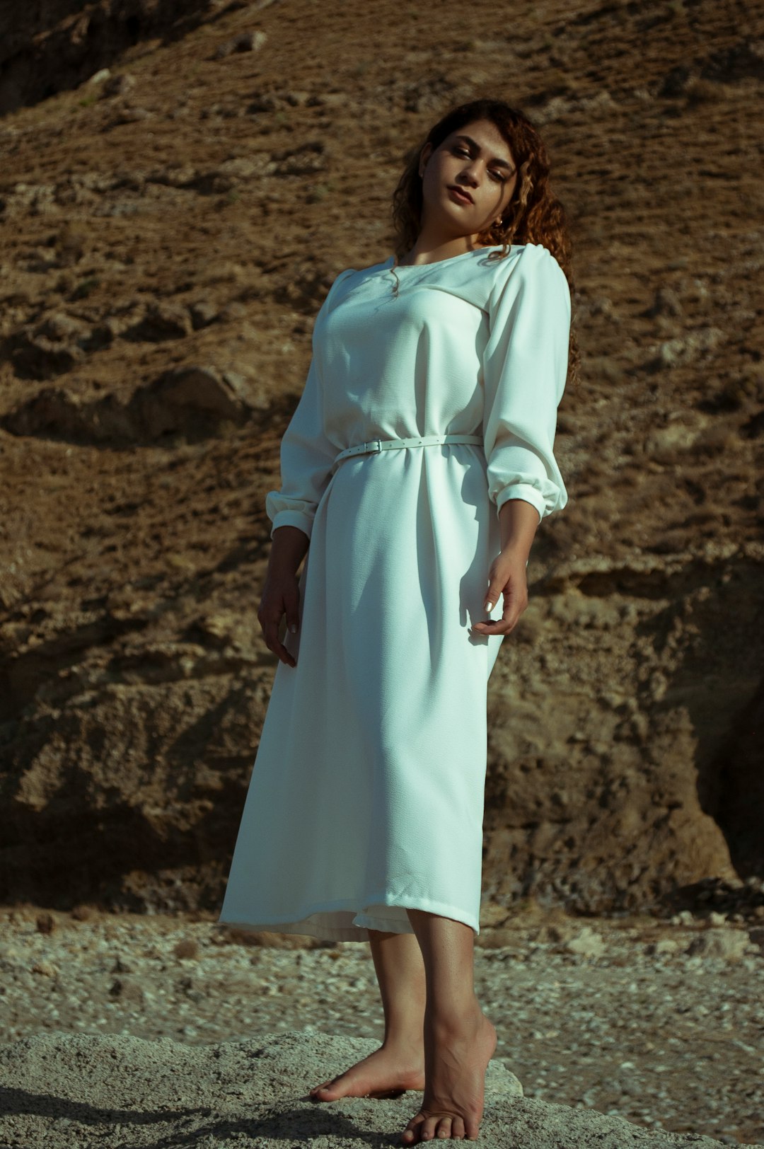 woman in white dress standing on brown sand during daytime