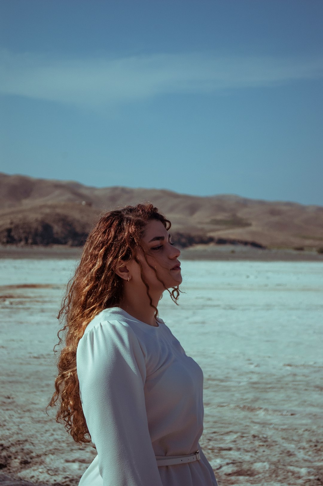 woman in white shirt standing near body of water during daytime