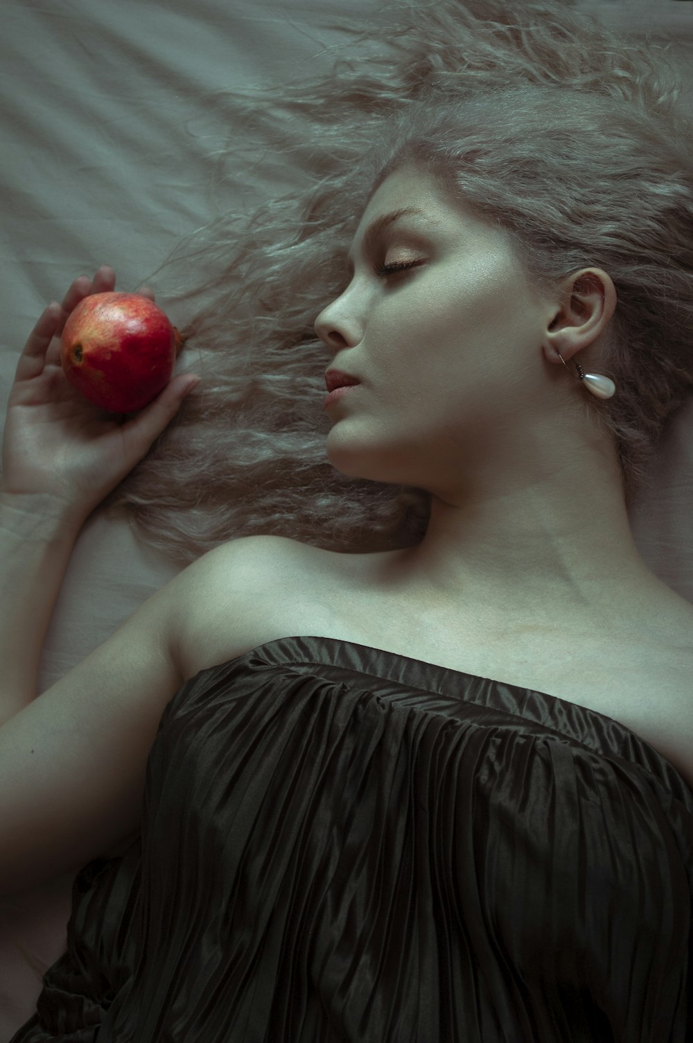 Femme en robe tube noire tenant une pomme rouge