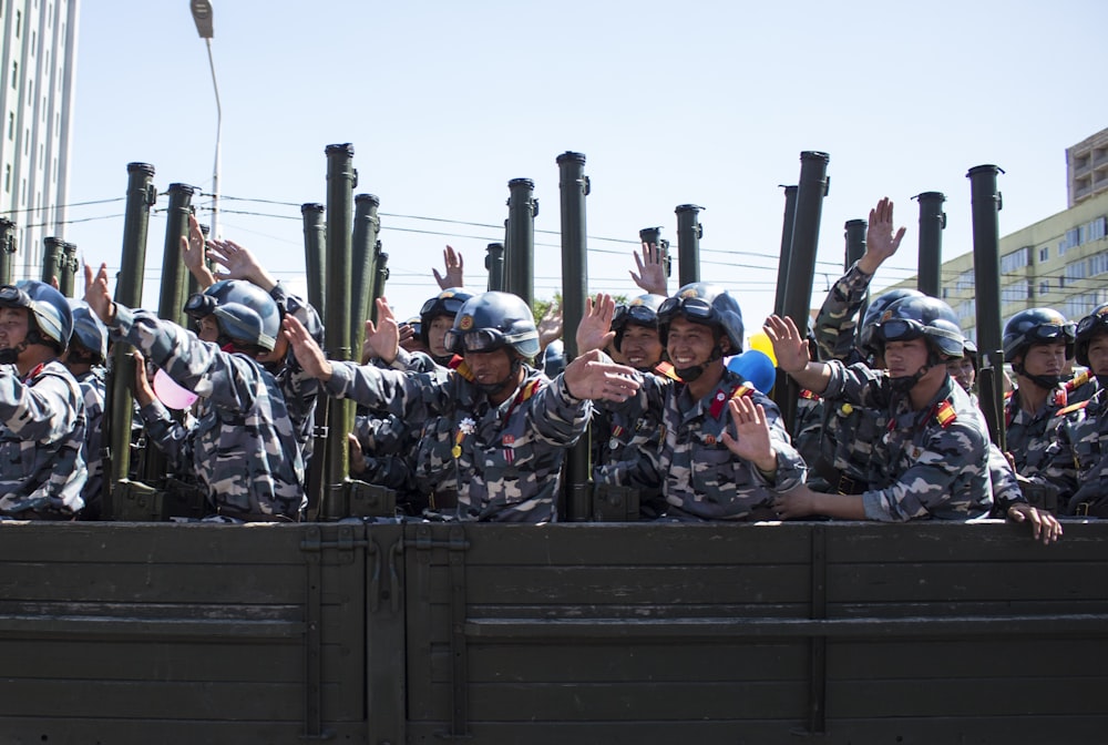 soldiers in brown and black camouflage uniform sitting on black metal frame during daytime