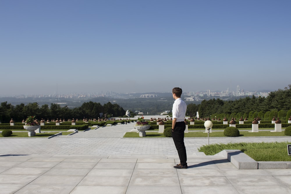 man in white shirt and black pants standing on gray concrete floor during daytime