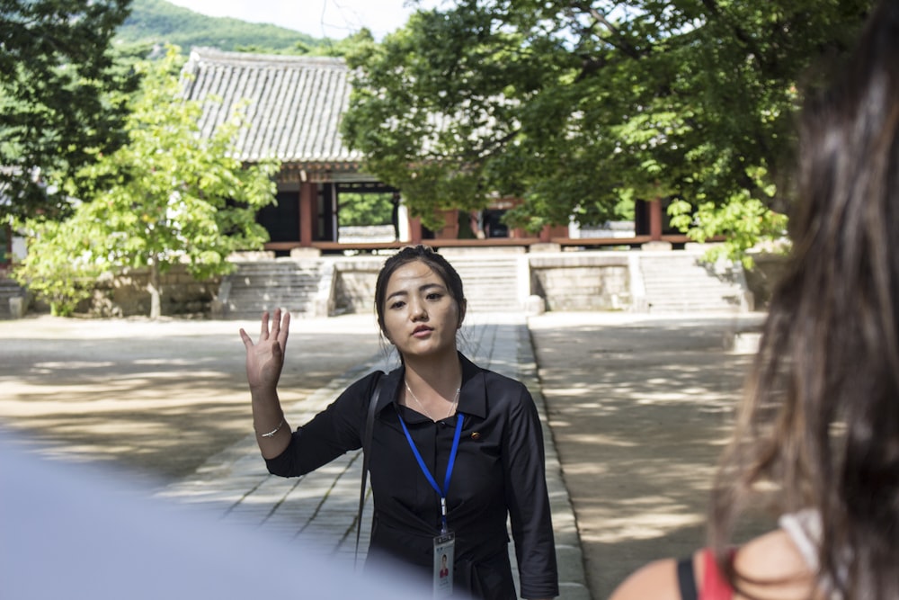 woman in black jacket standing near green trees during daytime