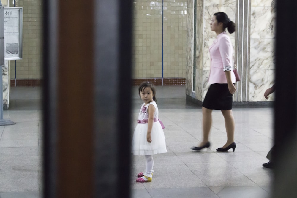 girl in white shirt and black skirt standing on white floor tiles