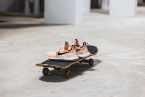 Sneakers casually placed by a skateboard on an urban concrete floor