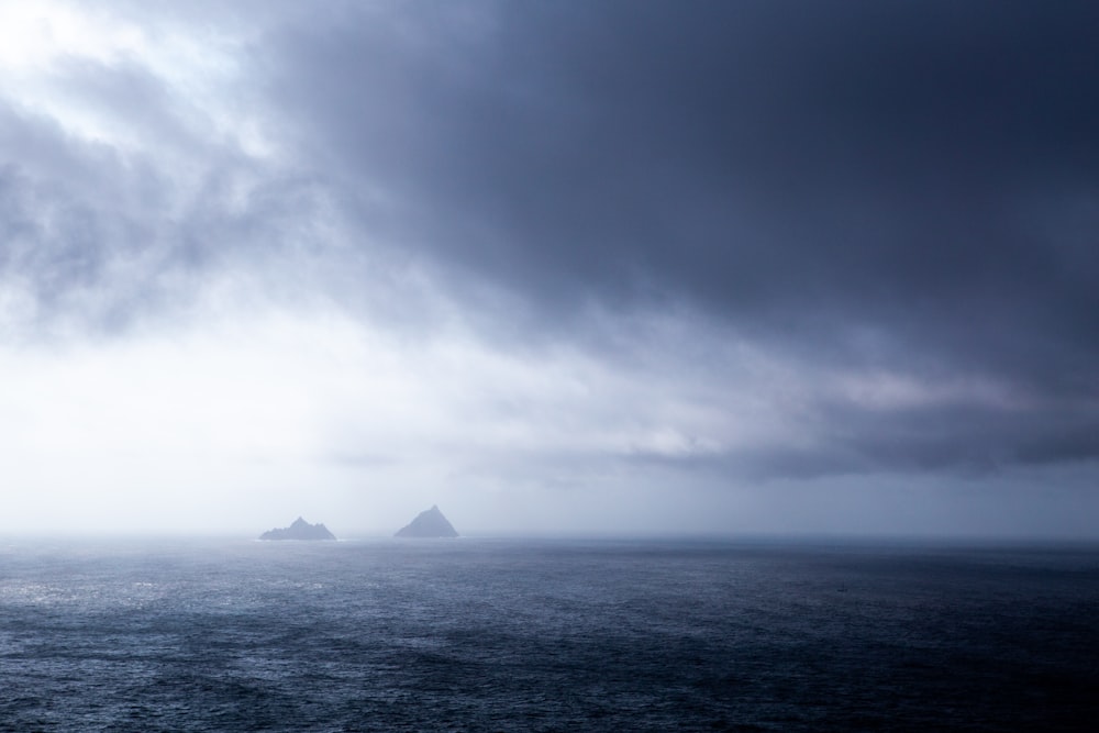 white sailboat on sea under white clouds