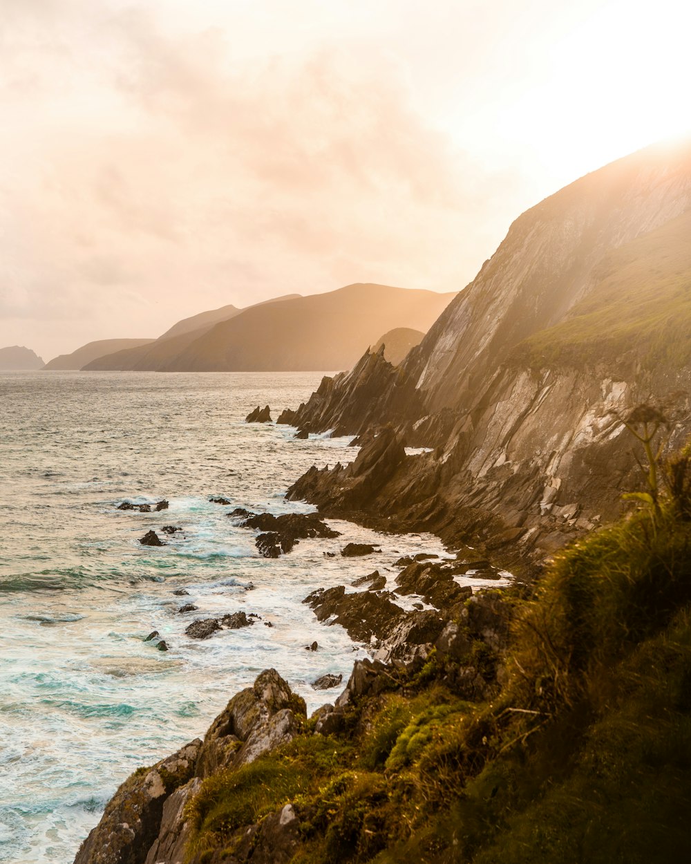 green and brown mountain beside sea during daytime