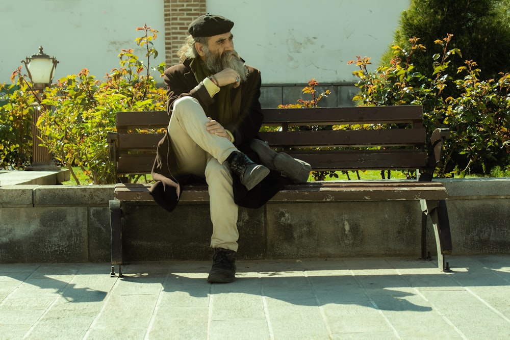 man in black jacket and black pants sitting on brown wooden bench during daytime