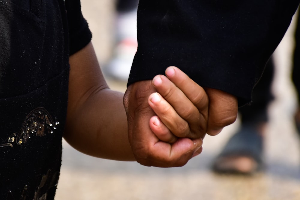 person in black t-shirt holding persons hand