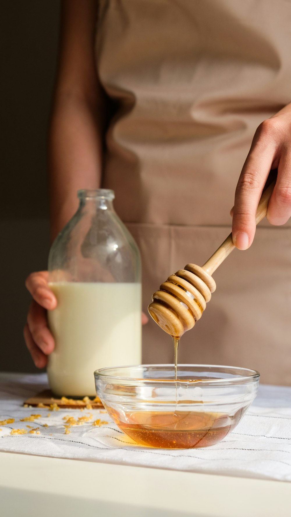 person holding clear glass jar with white liquid