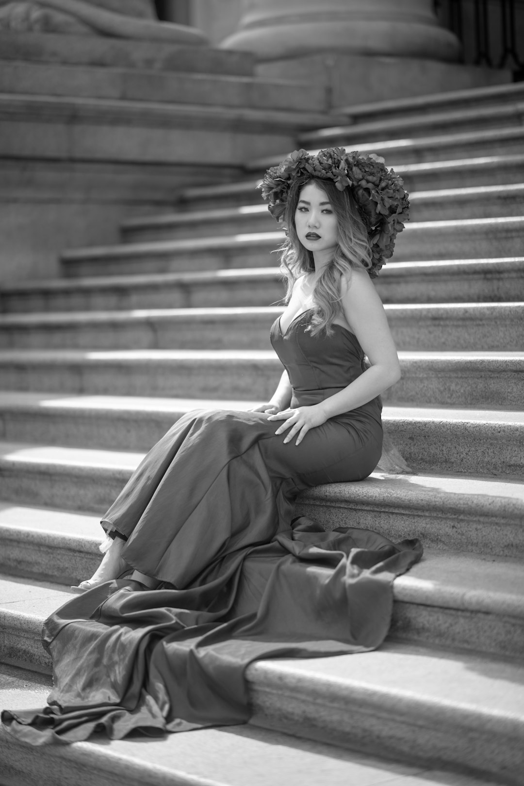 grayscale photo of woman in sleeveless dress sitting on stairs