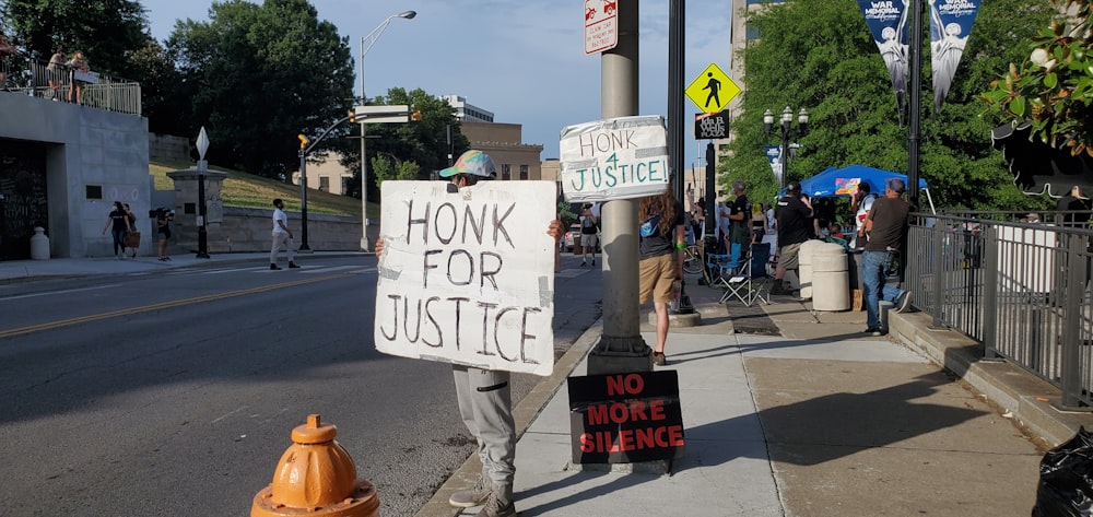 man in gray pants holding white and black signage