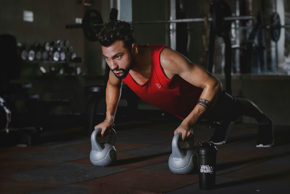 woman in red tank top and black pants sitting on black and white exercise equipment