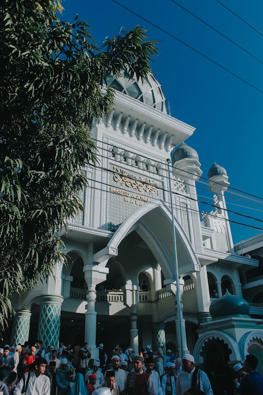 white concrete building near green trees under blue sky during daytime in Malang Indonesia