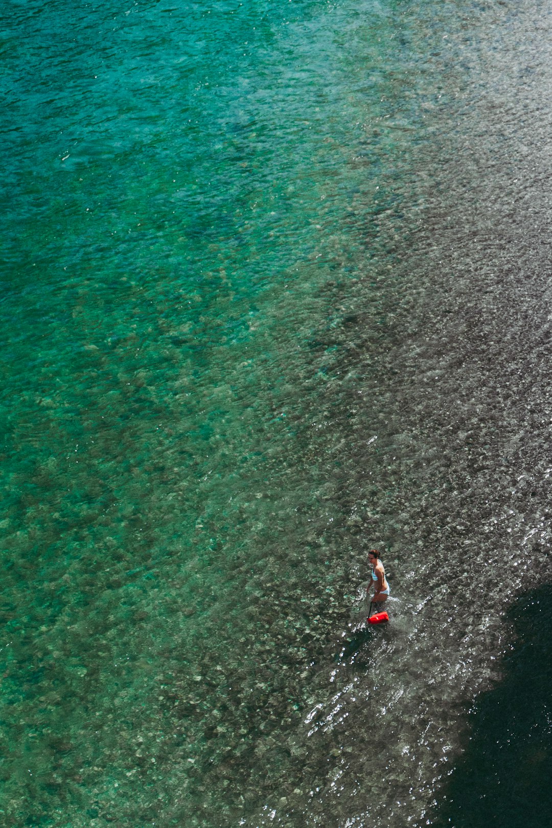 person in red shirt and black shorts standing on water during daytime