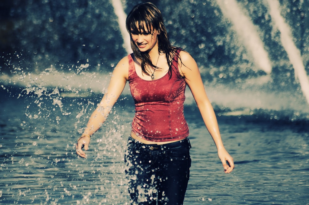 woman in red tank top and black pants standing on water