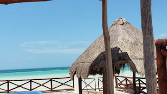 Sunlit guesthouse porch overlooking the turquoise ocean with soft beige sands in the background.