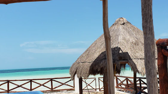 Sunlit guesthouse porch overlooking the turquoise ocean with soft beige sands in the background.