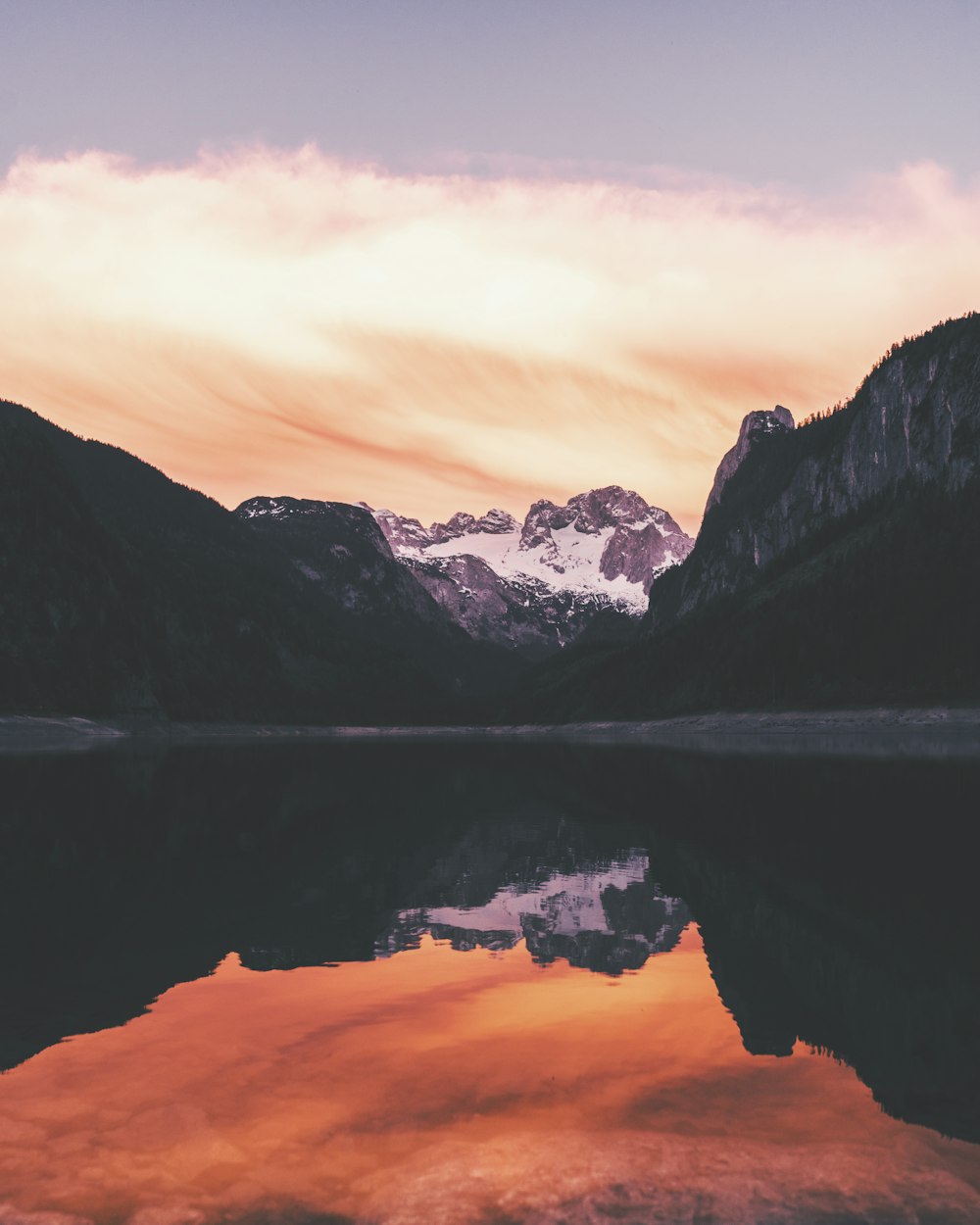 body of water near mountain during sunset