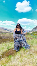 A vibrant photo of a confident woman wearing a flowing, fashionable dress outdoors on a sunny day.