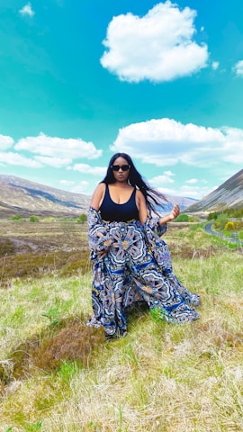 A vibrant photo of a confident woman wearing a flowing, fashionable dress outdoors on a sunny day.