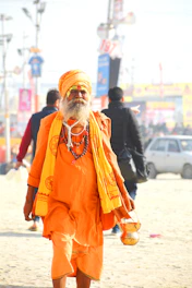 man in orange thobe standing on white sand during daytime