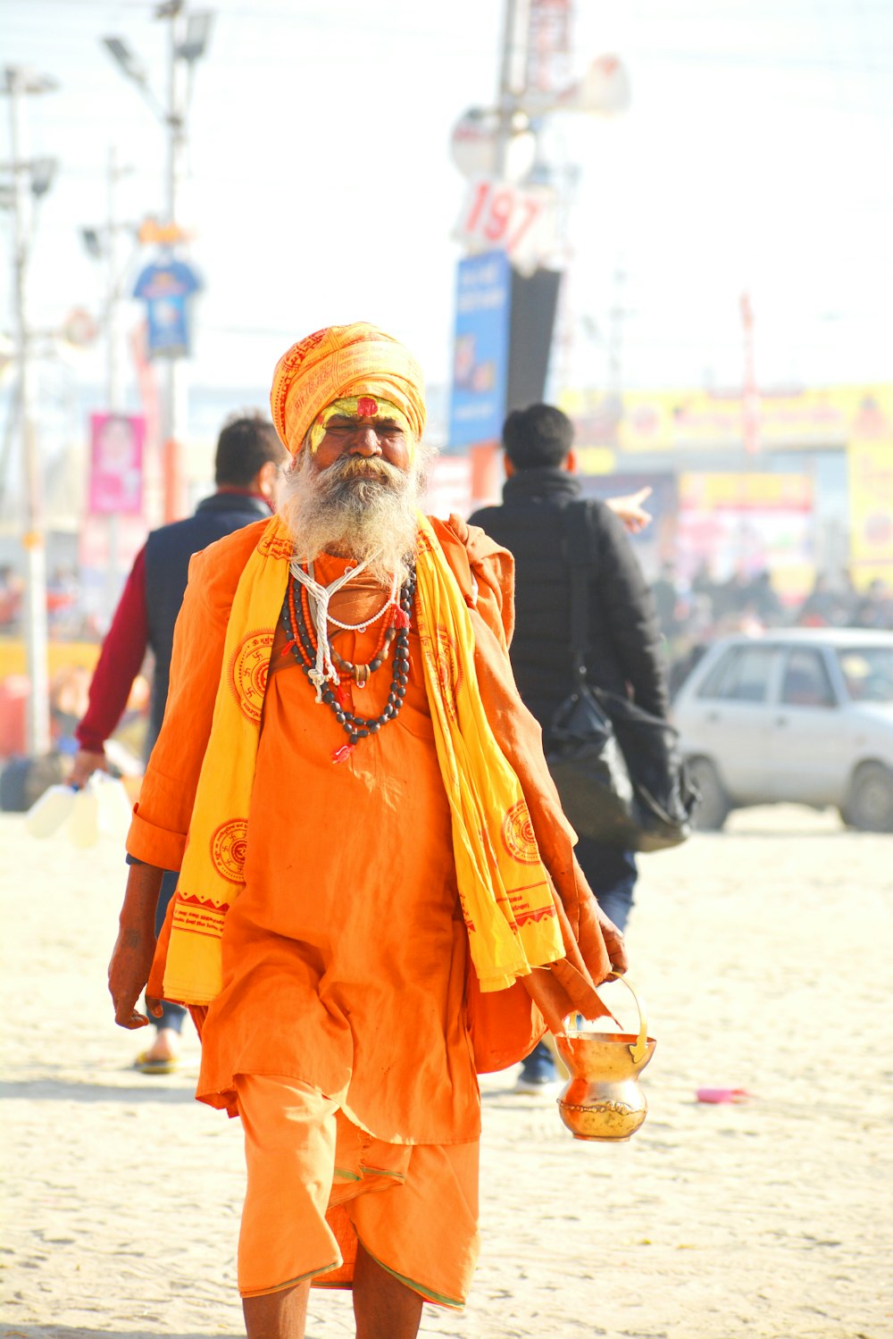man in orange thobe standing on white sand during daytime