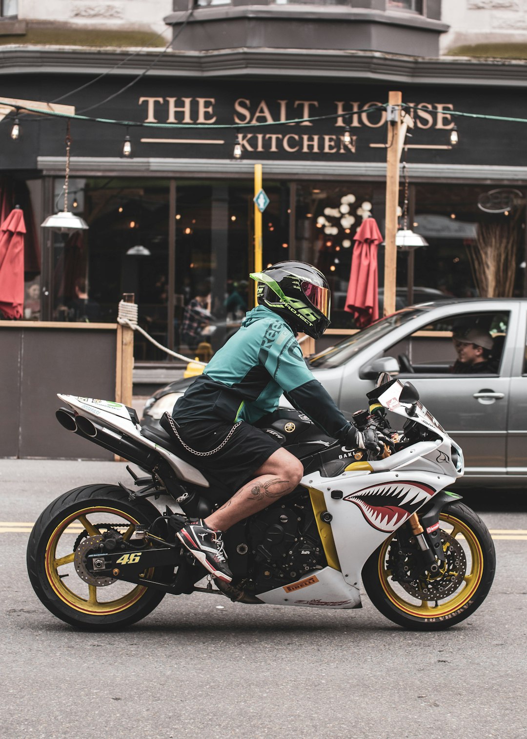 man in green jacket riding white and black sports bike