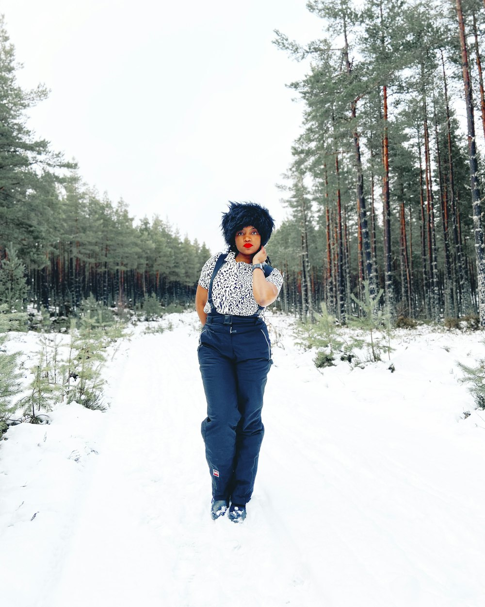 Mujer con camisa a cuadros blanca y negra y jeans vaqueros azules de pie sobre un suelo cubierto de nieve