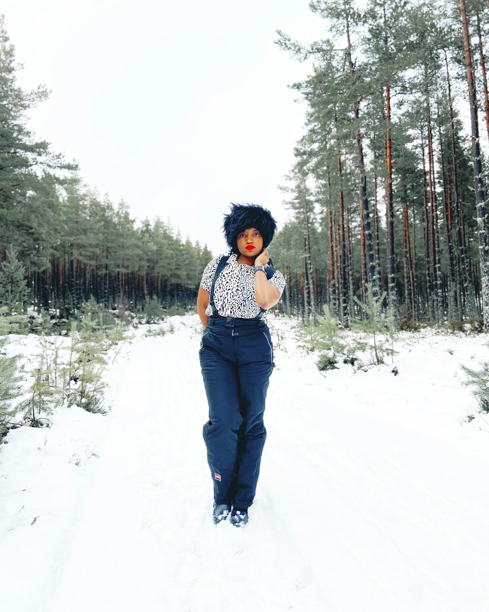 woman in white and black plaid shirt and blue denim jeans standing on snow covered ground
