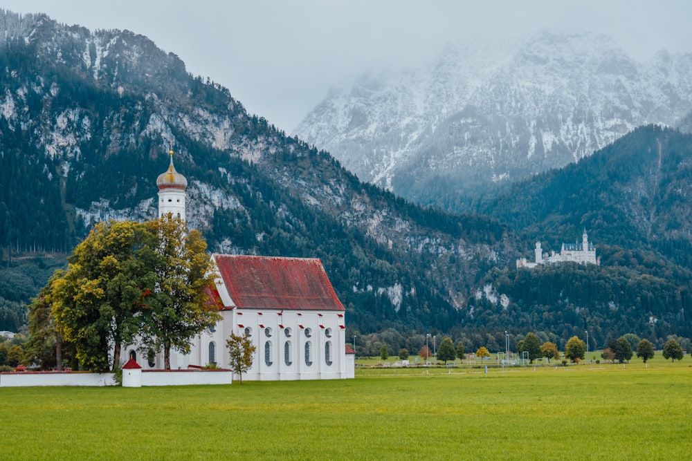 red and white house on green grass field near mountain during daytime