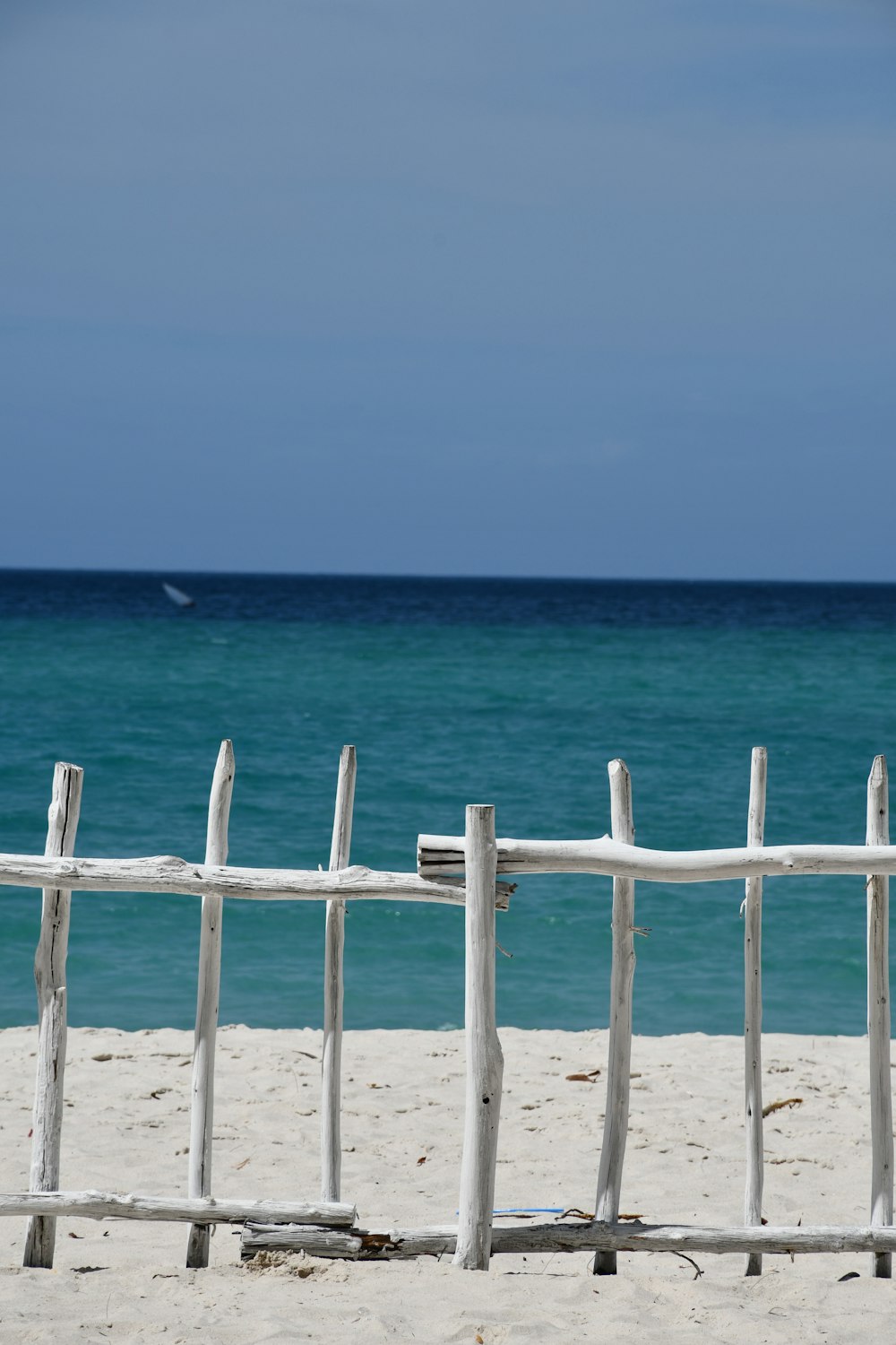 昼間のビーチの白い木製のフェンス