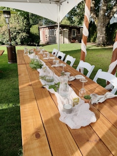 An elegant outdoor event setup with natural wood tables and soft lighting, ready for a bespoke celebration.