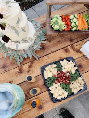 A beautifully arranged catering spread featuring colorful salads, roasted meats, and fresh desserts on rustic wooden tables.