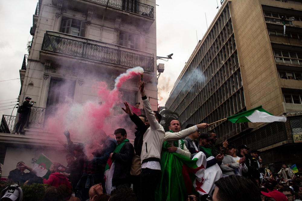 people gathering on street with red smoke