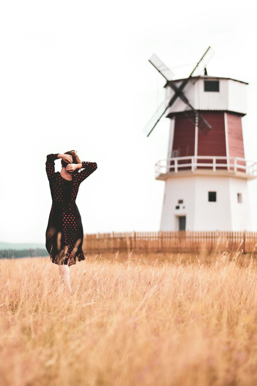 woman in black dress standing near red and white lighthouse