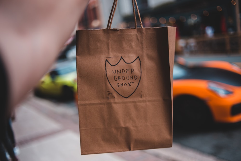 brown paper bag on persons hand