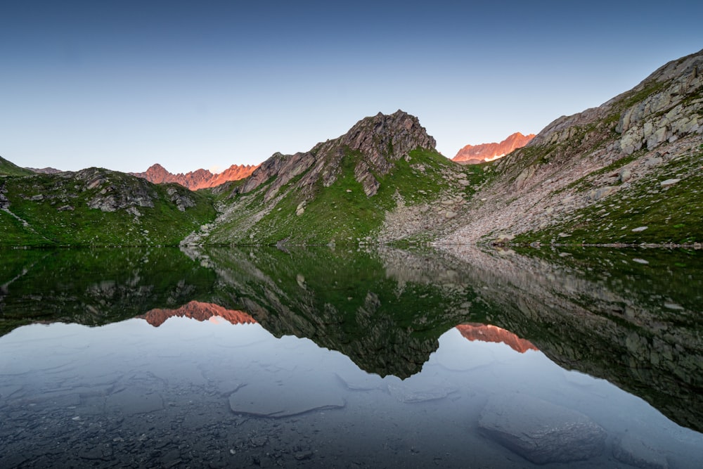 green and brown mountain beside body of water during daytime