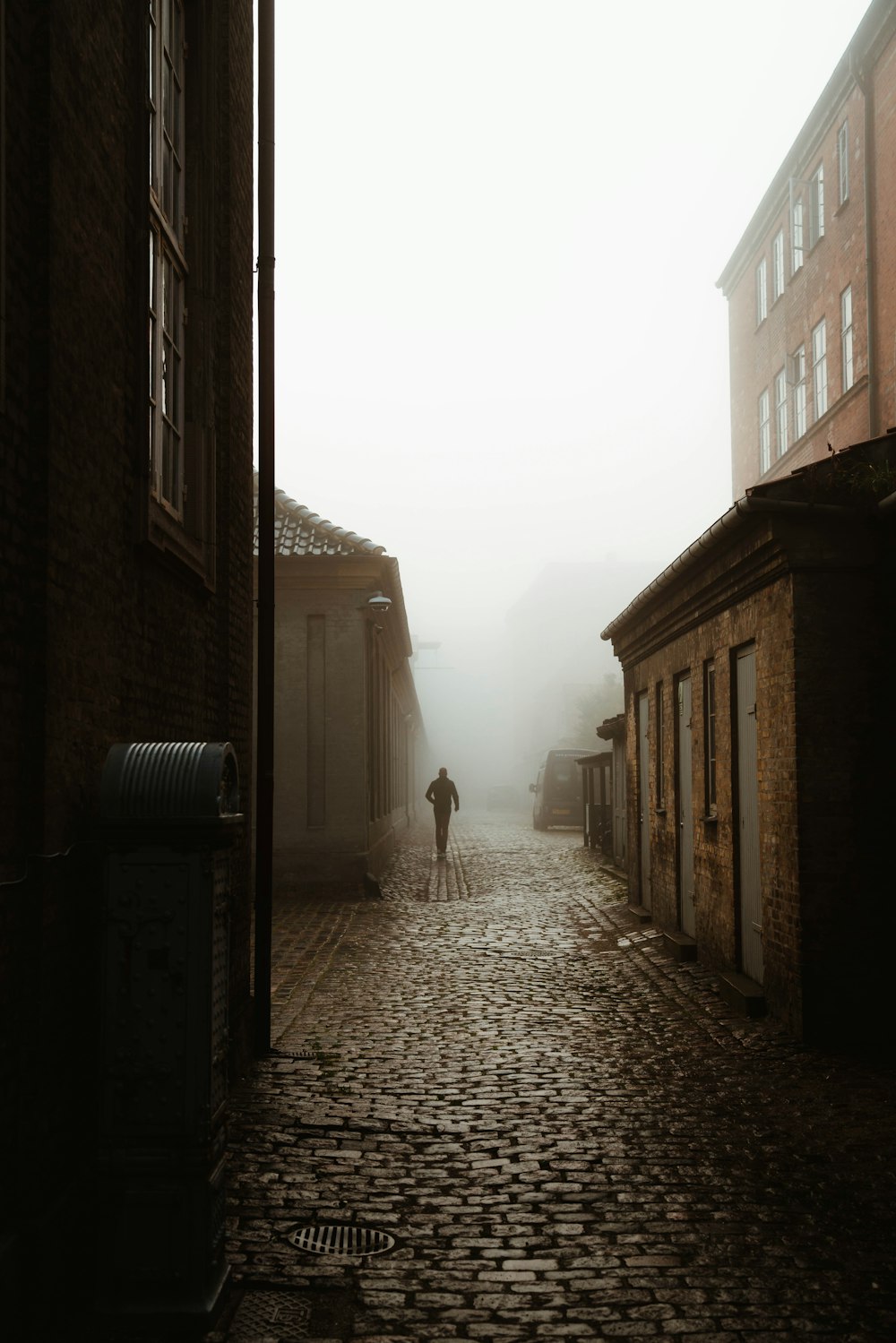 person walking on pathway between buildings during daytime