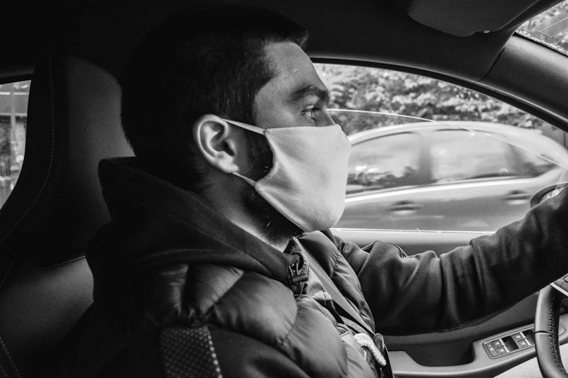 black and white photo of a man driving a car