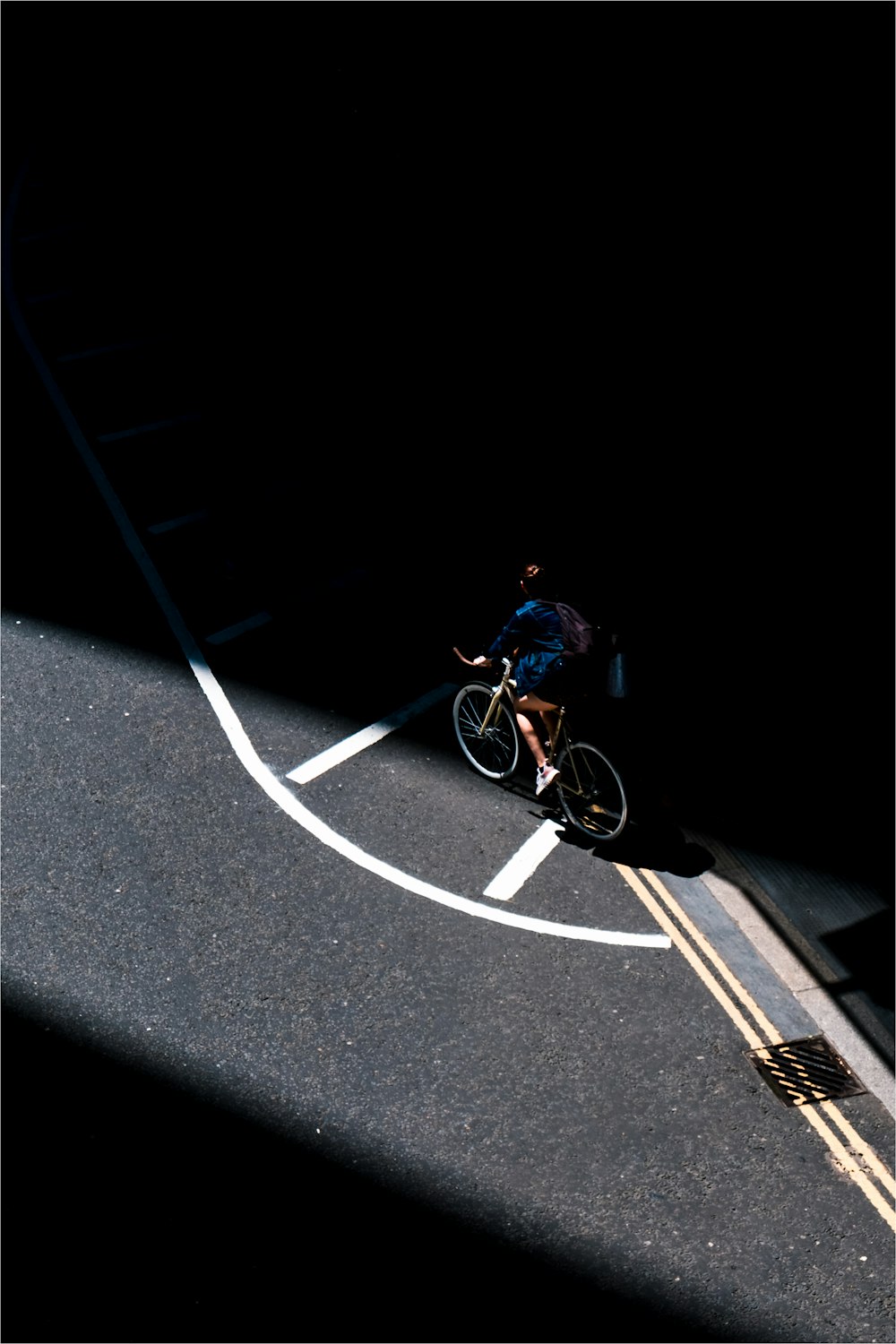 homem na jaqueta azul que monta a bicicleta na estrada do asfalto preto durante a noite