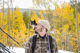 man in white hat and plaid shirt with black and white cat on his head