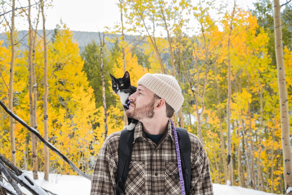 man in white hat and plaid shirt with black and white cat on his head