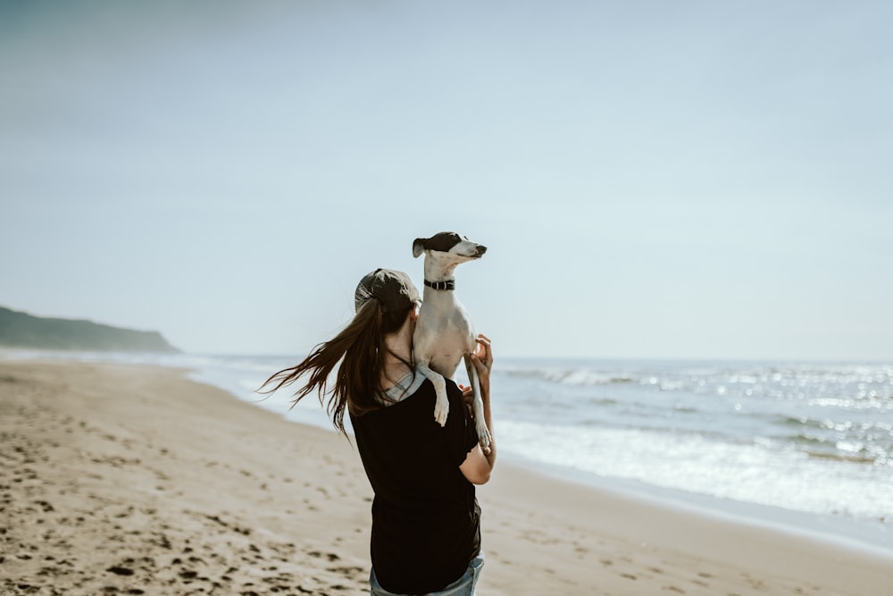 Femme en débardeur noir et pantalon noir debout sur le rivage de la plage pendant la journée