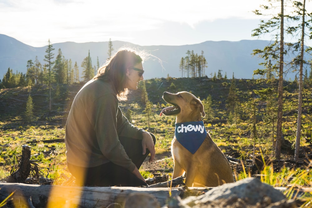 woman in black and white adidas shirt sitting beside brown short coated dog during daytime